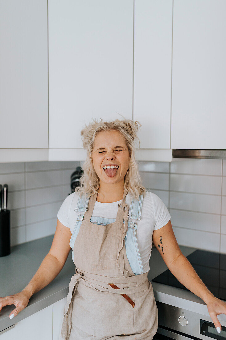 Frau in der Küche streckt ihre Zunge heraus