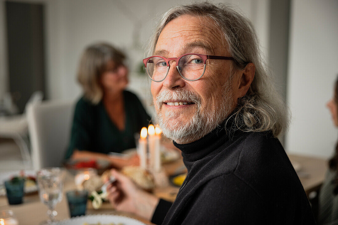 Porträt eines älteren Mannes, der mit seiner Familie zu Abend isst