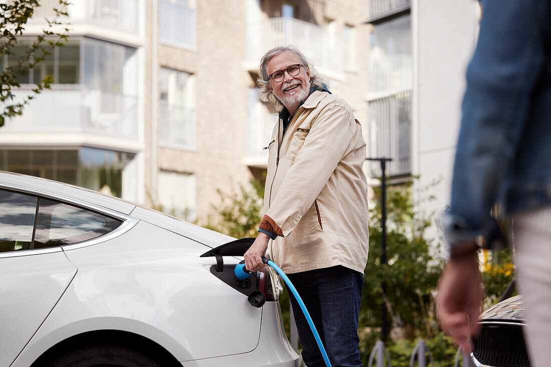 Senior man charging electric car