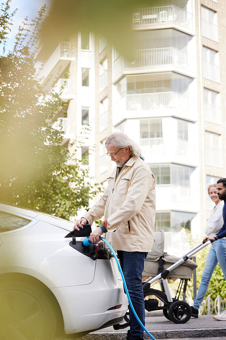 Senior man charging electric car