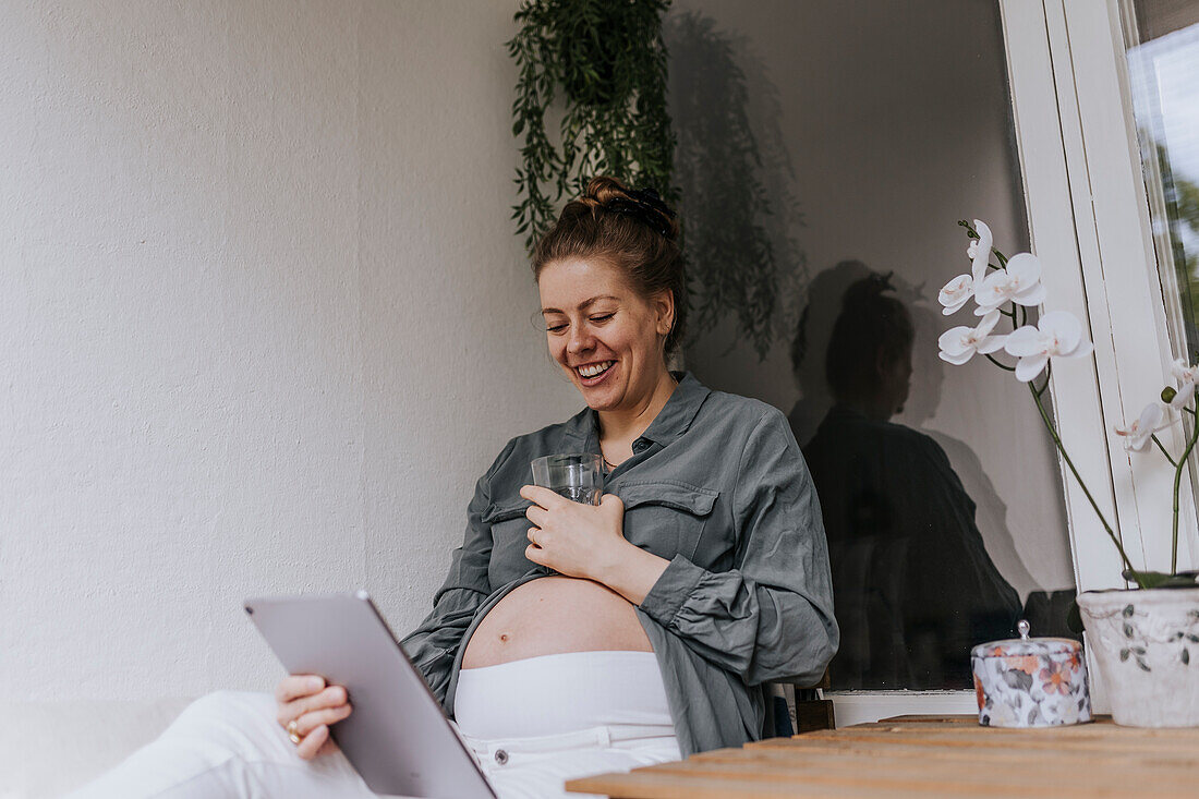 Schwangere Frau mit digitalem Tablet