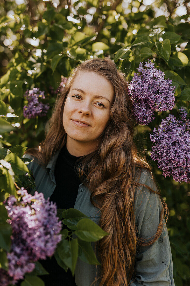 Portrait of smiling woman standing against lilac bush