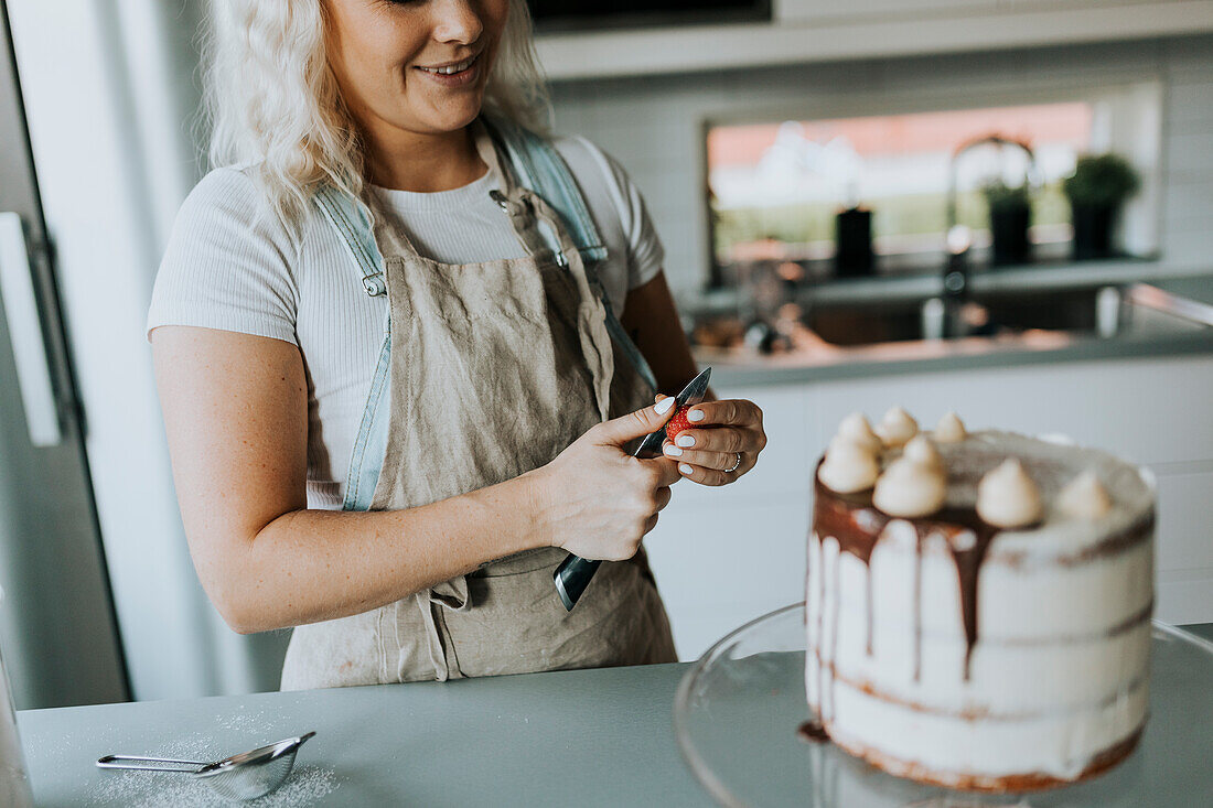 Frau in der Küche beim Verzieren von Kuchen