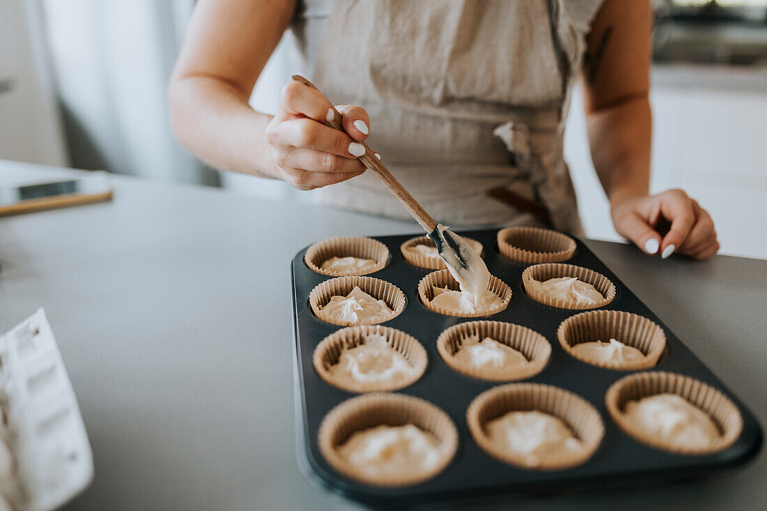 Frau in Küche bei der Zubereitung von Cupcakes