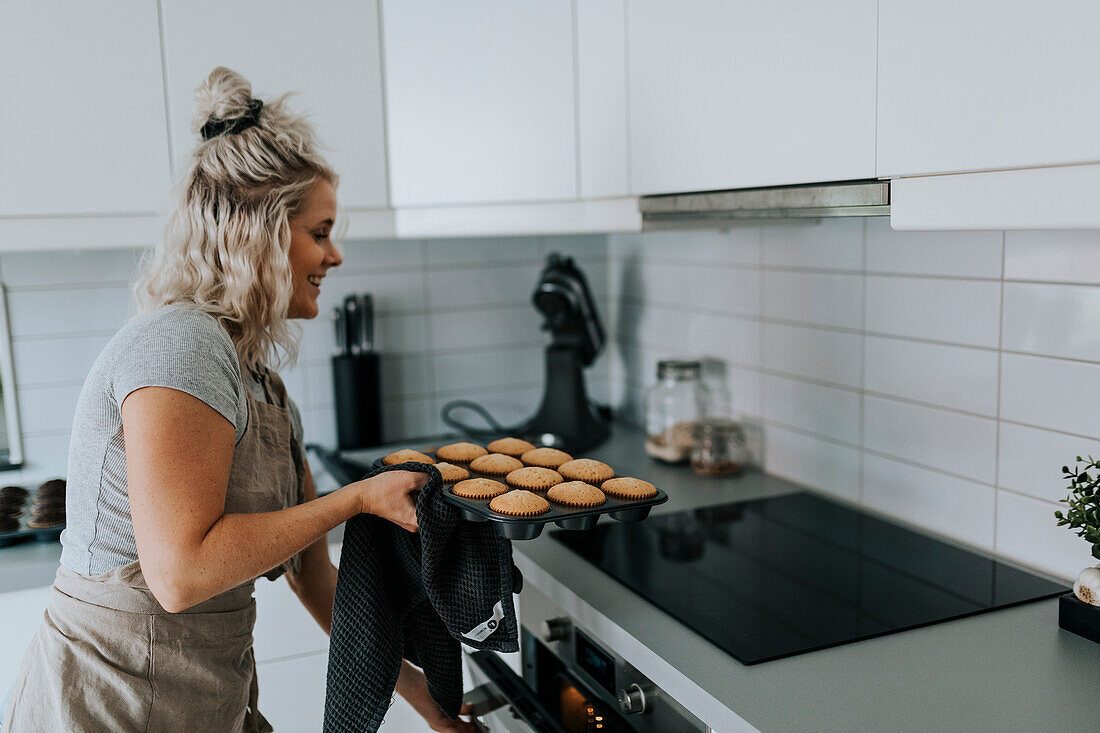 Woman in kitchen preparing cupcakes