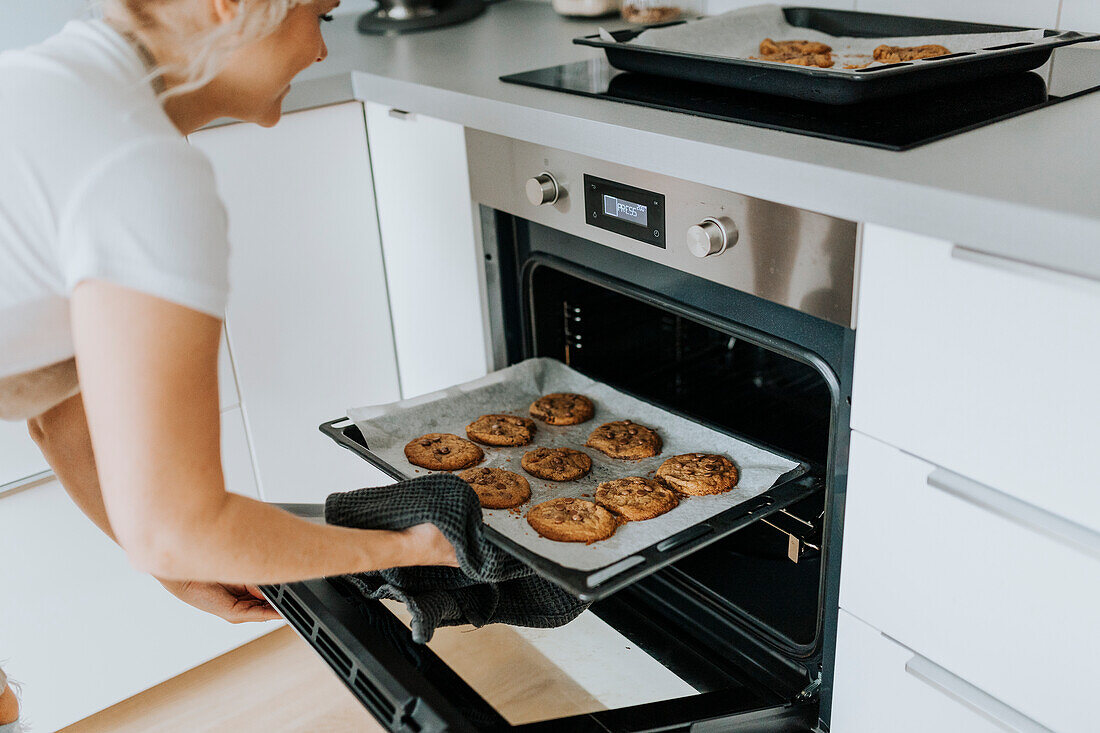 Woman taking cookies out of oven