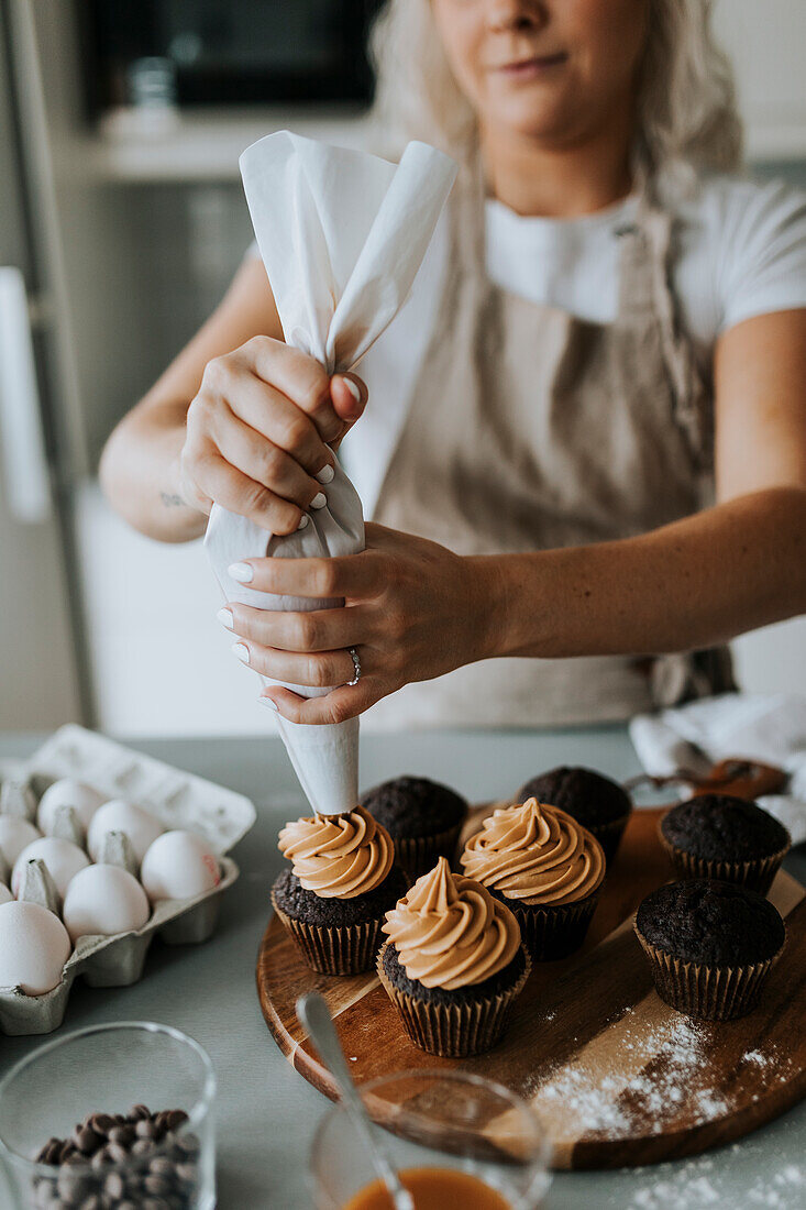 Woman putting icing on cupcakes