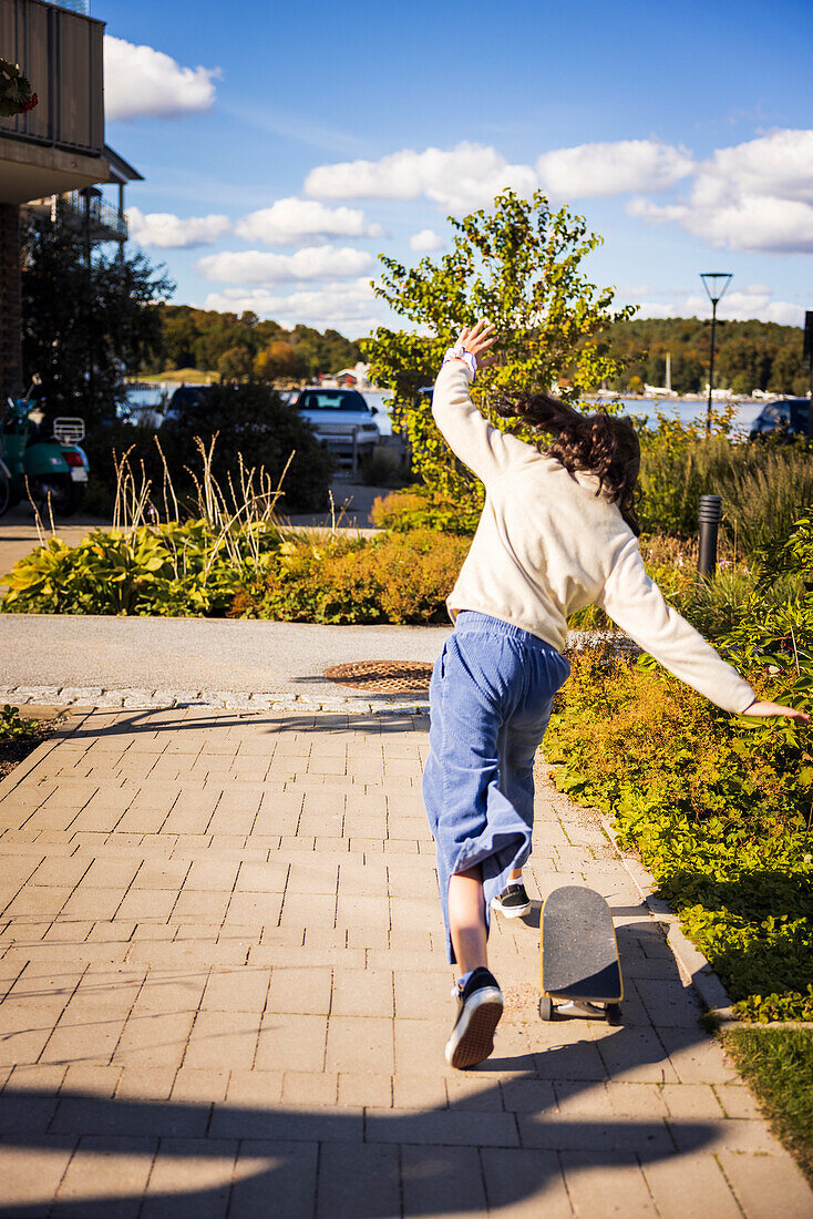 Rear view of girl falling off of skateboard