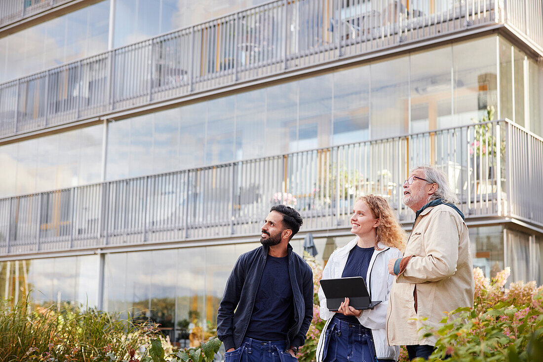 Men and woman with laptop looking at buildings