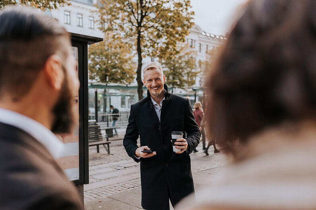 Lächelnder Geschäftsmann hält Einwegbecher