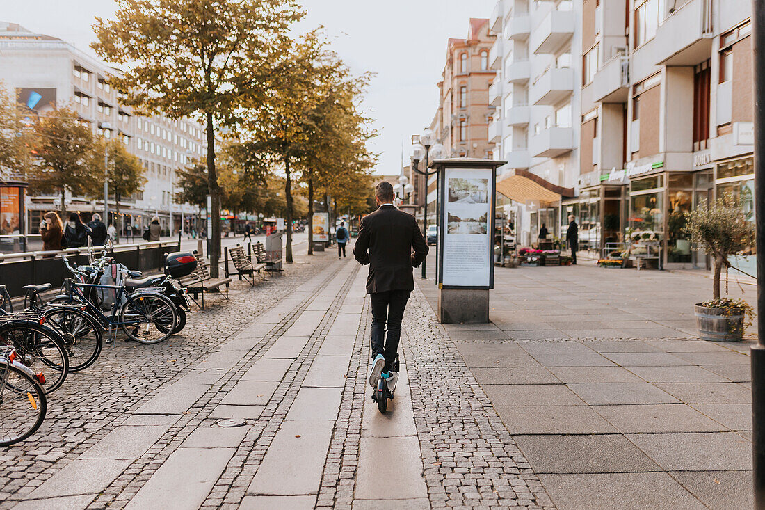 Rear view of man using scooter