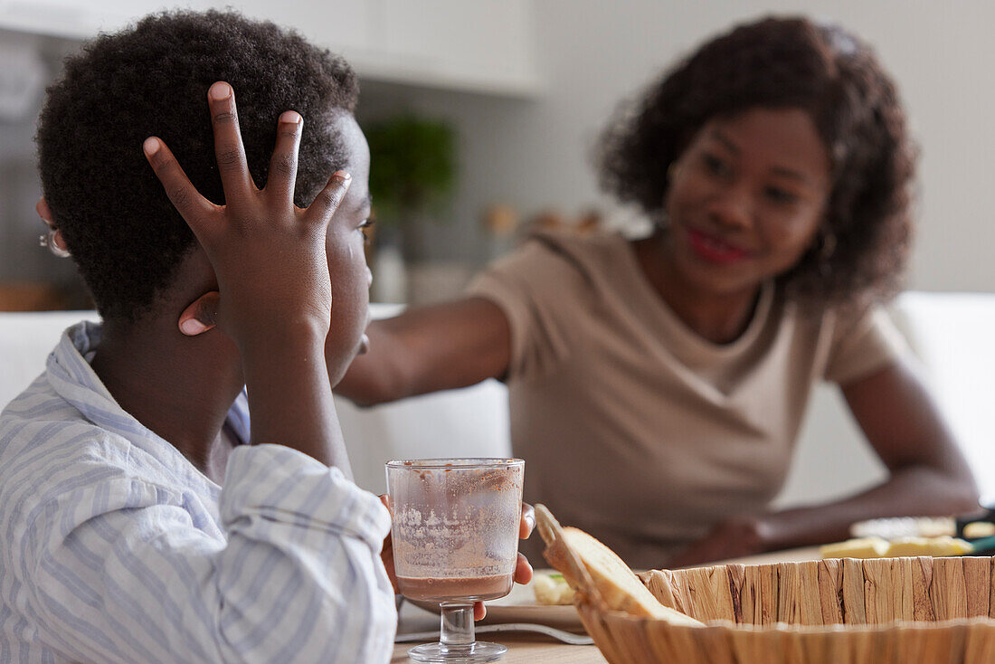 Mother and son sitting at table and eating breakfast