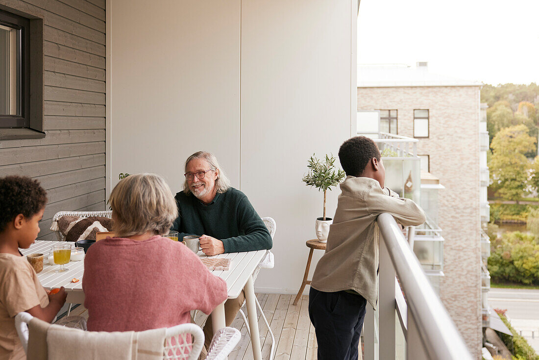 Familie sitzt am Tisch auf dem Balkon