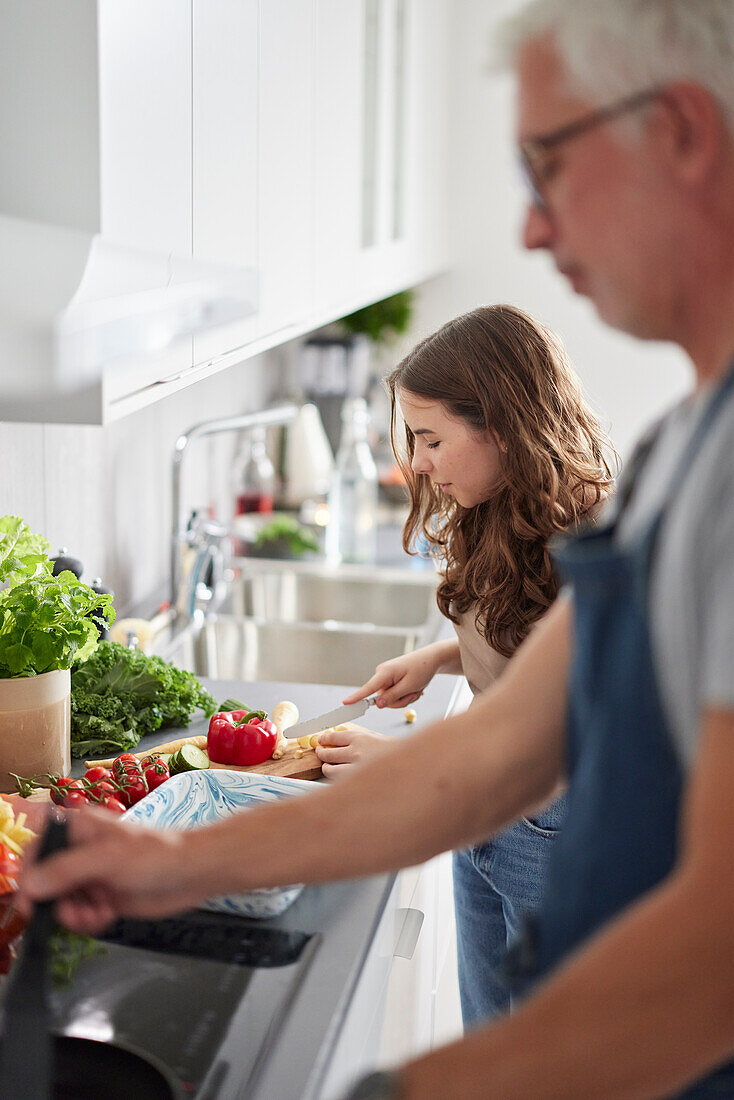 Father and daughter preparing food in kitchen