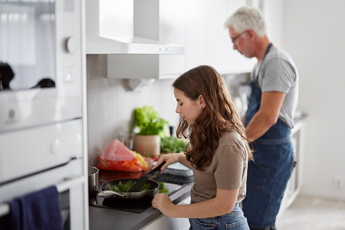 Father and daughter preparing food in kitchen