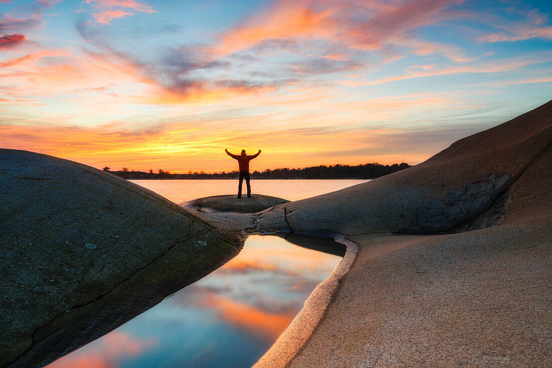 Person on rocky coast at sunset