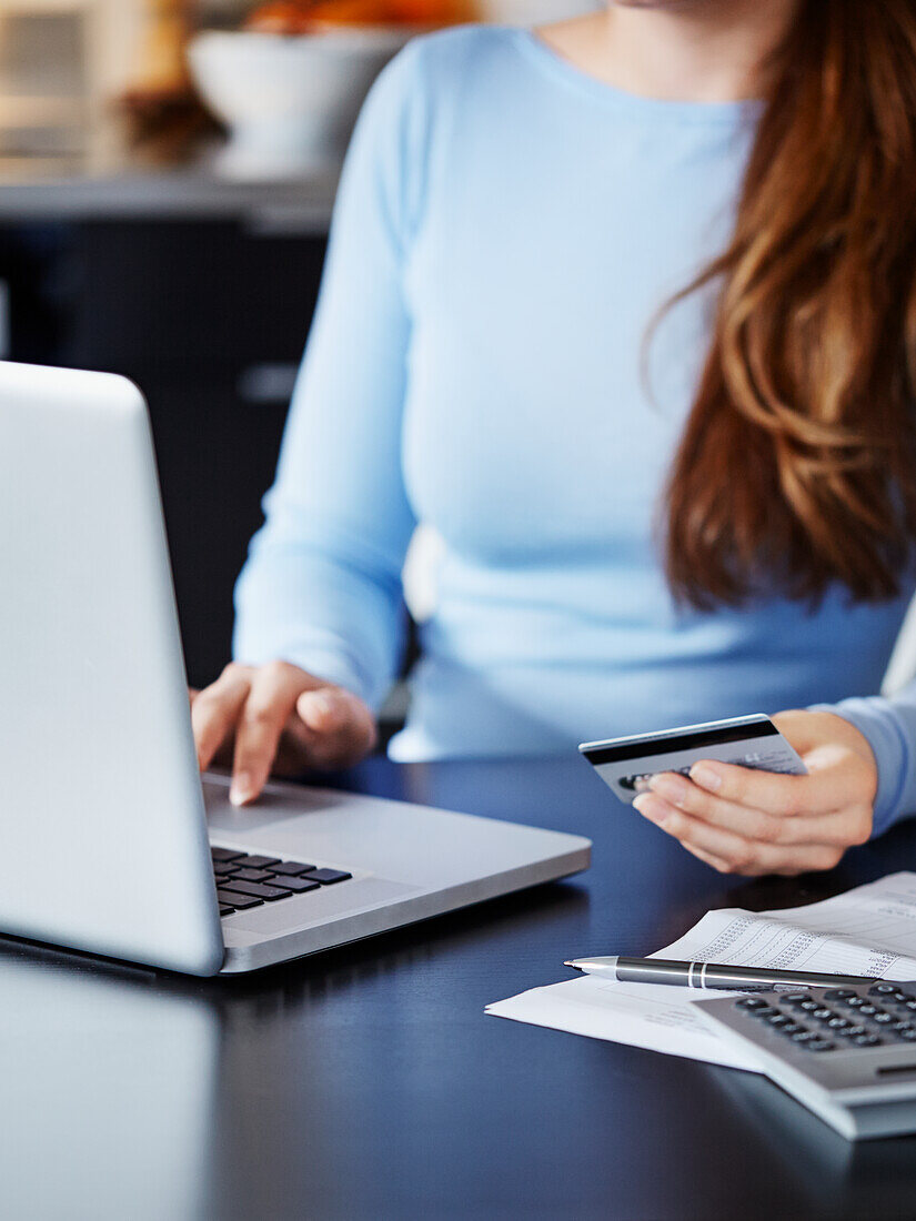 Woman holding credit card and using laptop