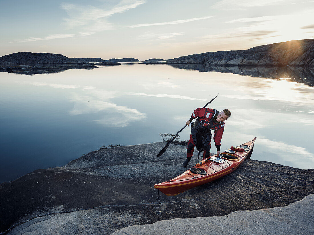 Man with kayak on rocky coast