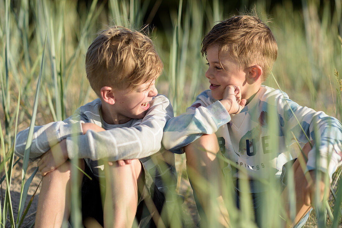 Smiling boys sitting in grass