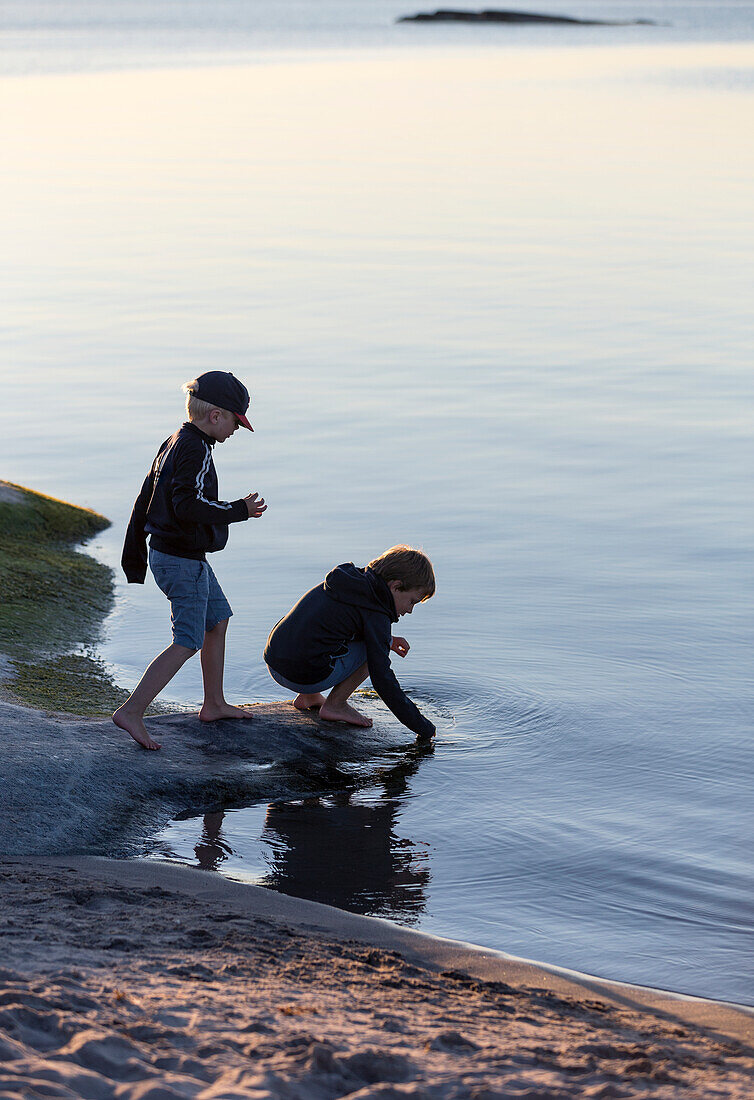 Two boys playing by water