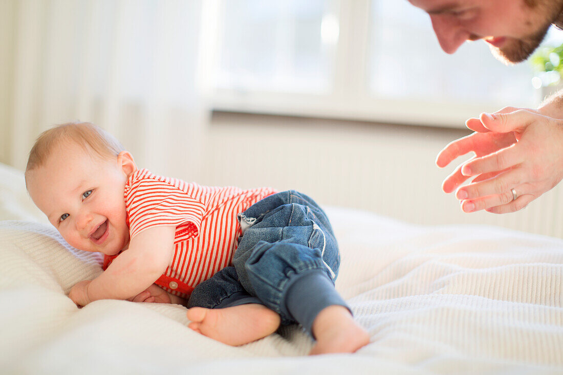 Father playing with son on bed