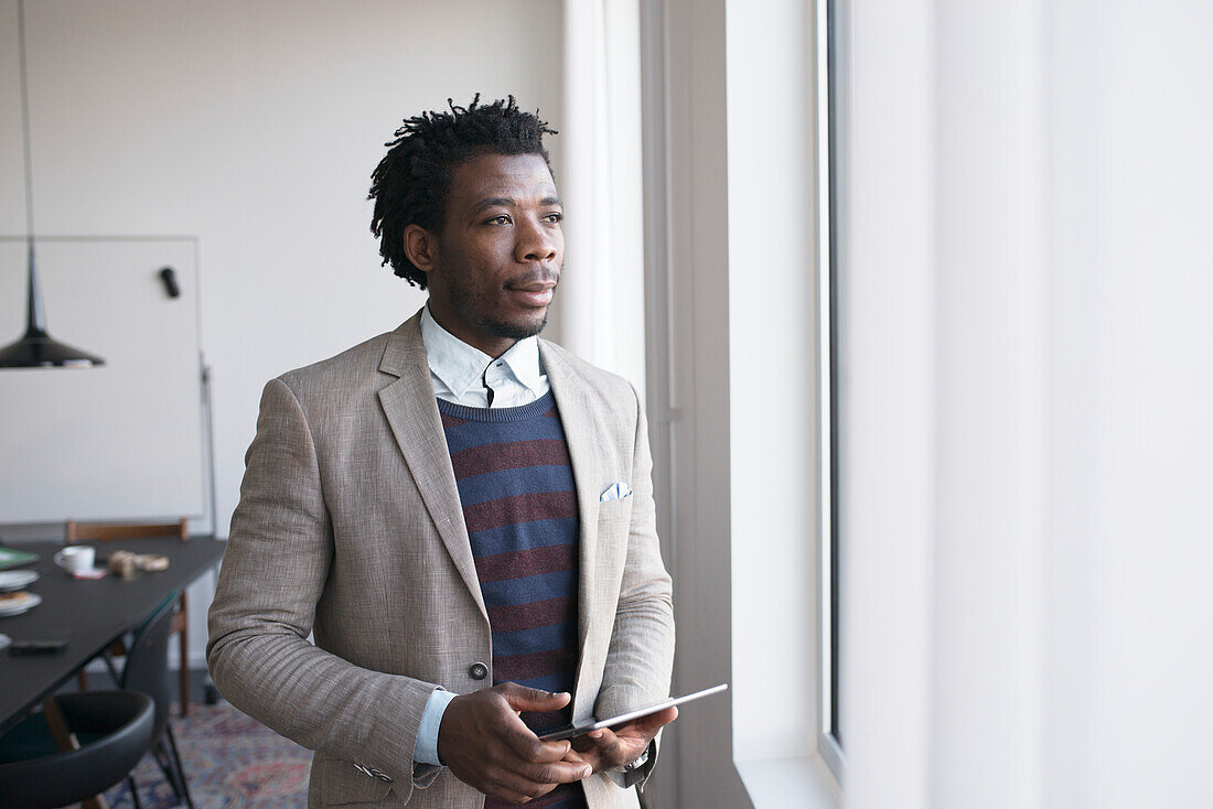 Man holding digital tablet, looking through window