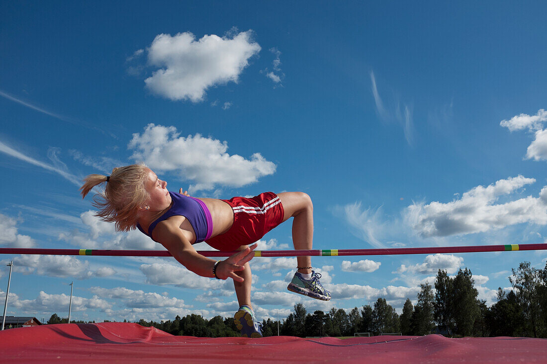 Teenage girl jumping over pole