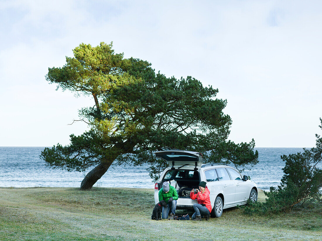 People near car at sea