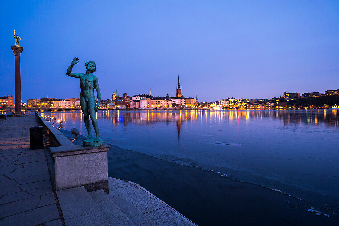 Männliche Statue am Meer. Das Rathaus von Stockholm im Hintergrund, Schweden