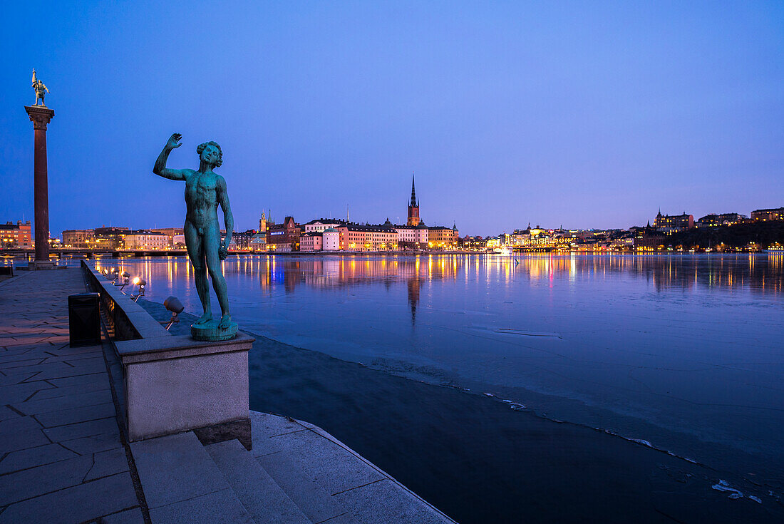 Male statue at sea. Stockholm City Hall on background, Sweden