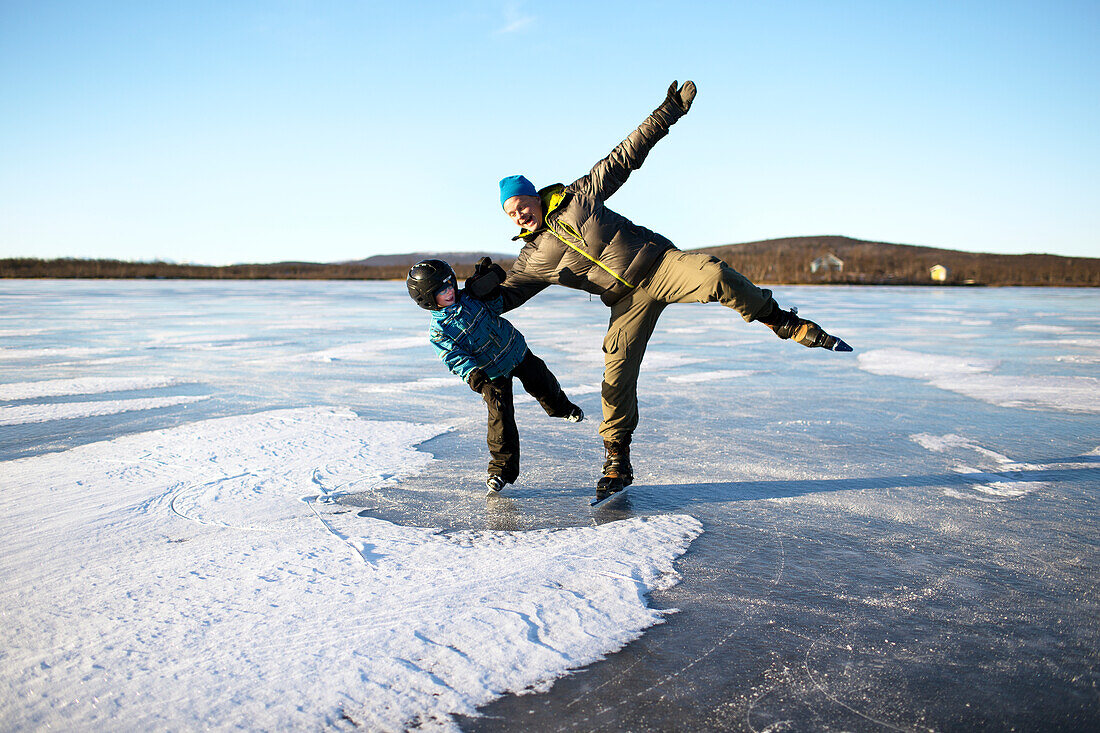 Vater mit Sohn beim Schlittschuhlaufen auf einem zugefrorenen See
