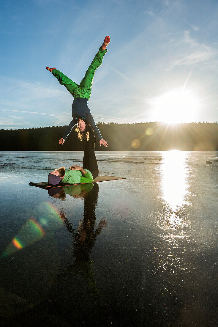 Paar macht Yoga auf zugefrorenem See