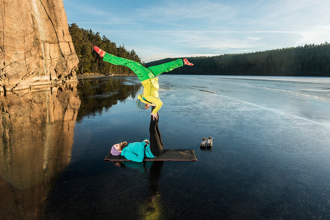 Paar macht Yoga auf zugefrorenem See