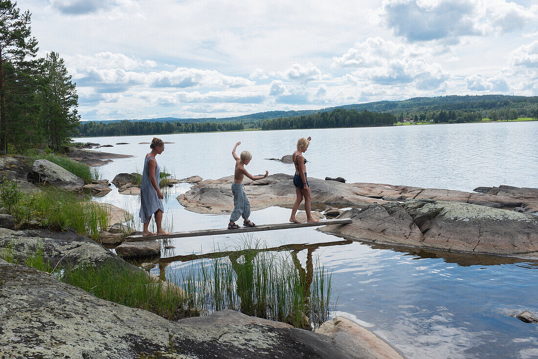 Mother with children crossing log bridge