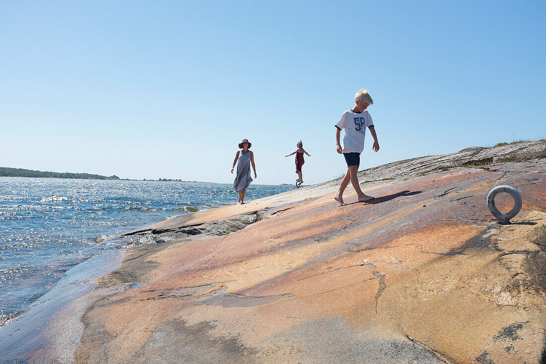 Mutter geht mit Kindern am Meer spazieren