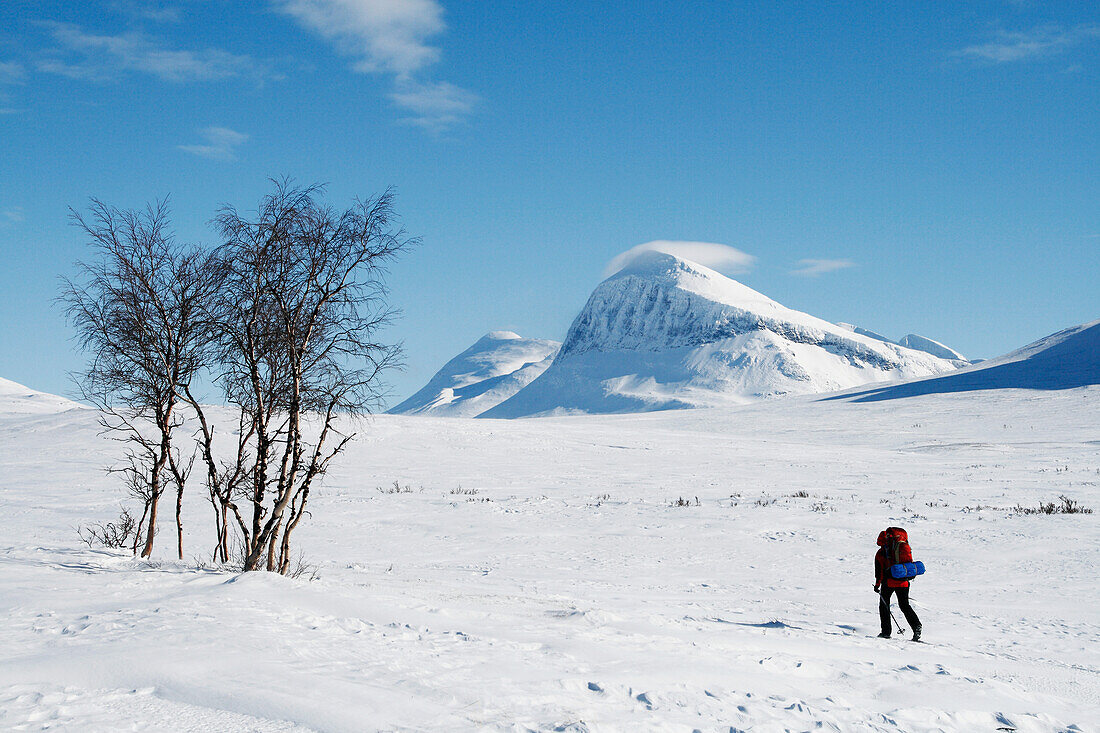 Tourist cross country skiing against mountain scenery