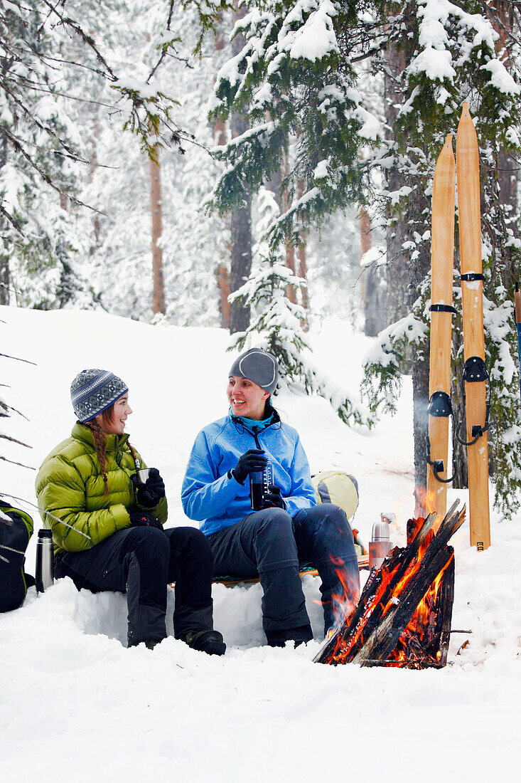 Women resting by fireplace in winter forest