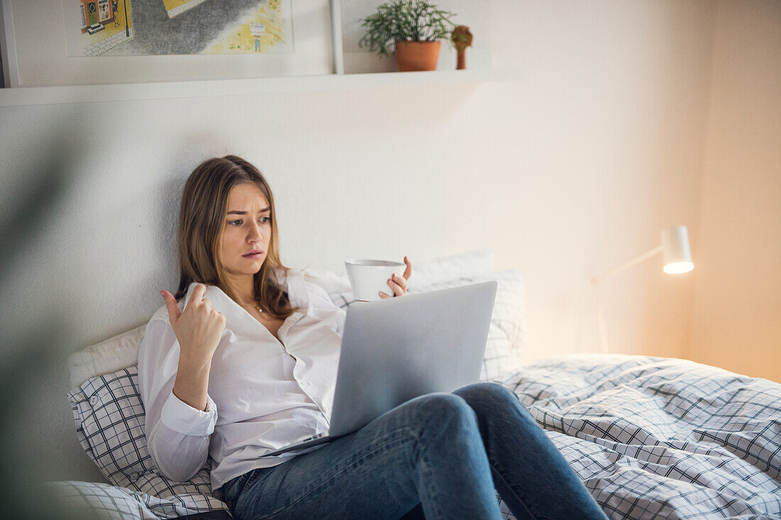 Young woman using laptop in bed