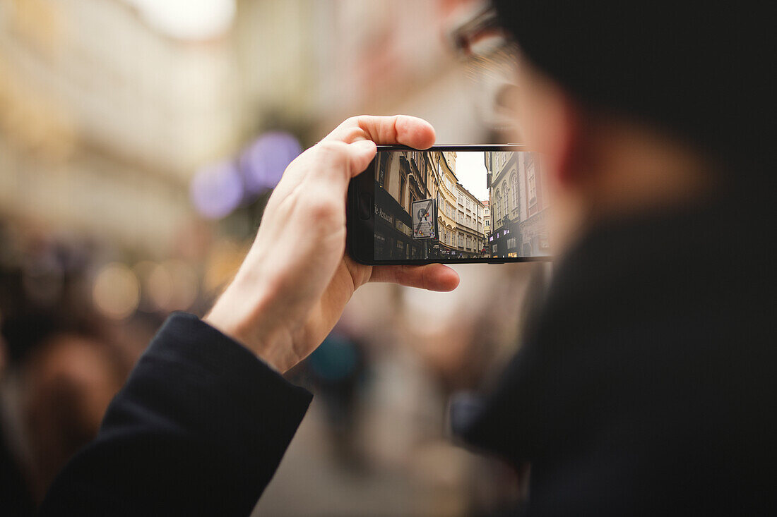 Nahaufnahme einer Hand, die eine Straße in der Stadt fotografiert