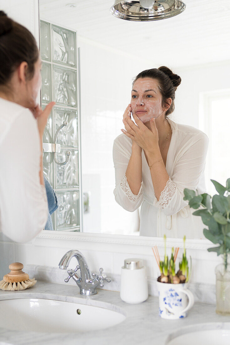 Woman in bathroom washing face