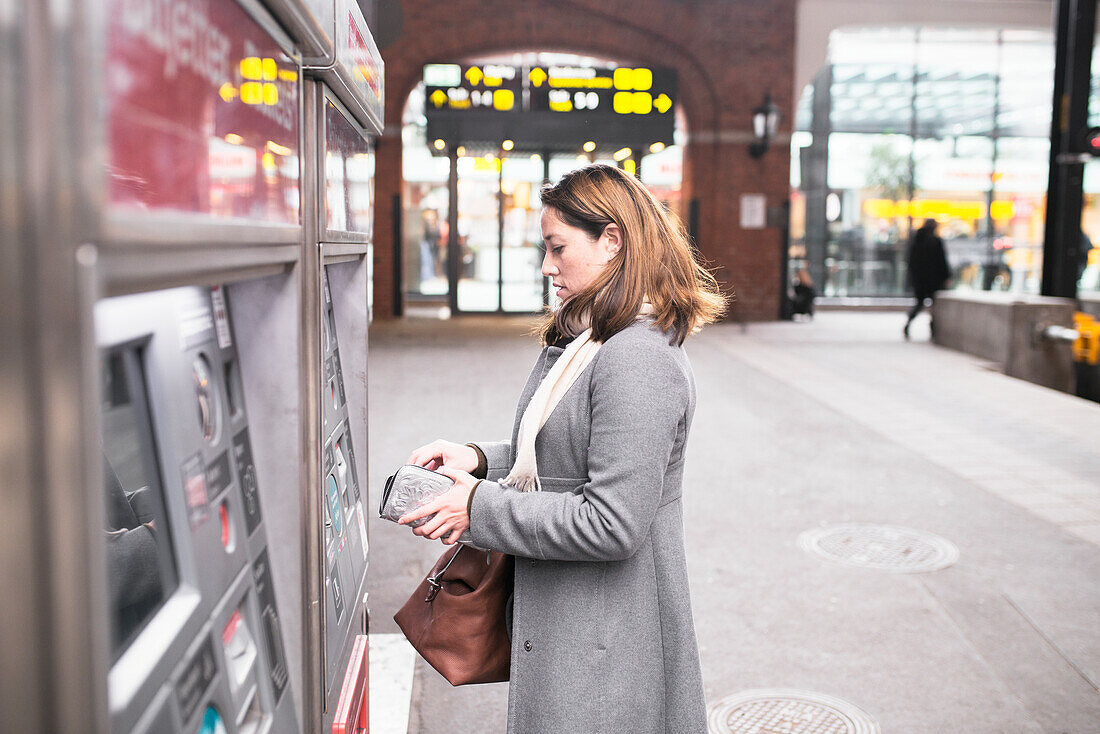 Frau kauft Fahrkarte im Fahrkartenautomaten