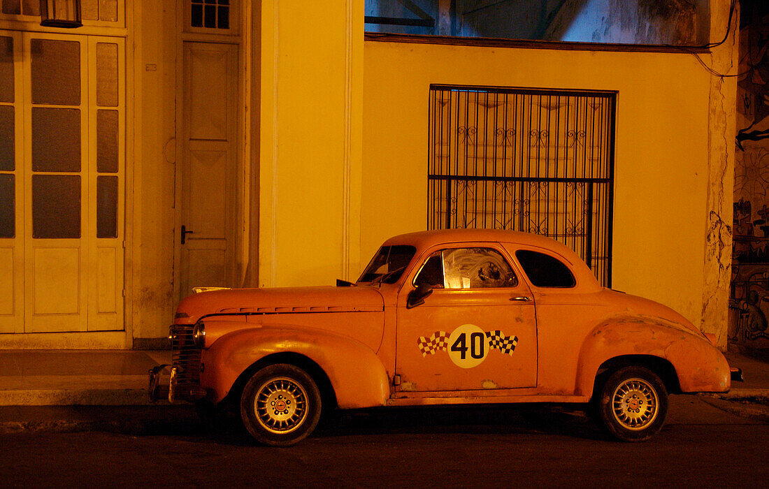 Vintage car in front of building at night