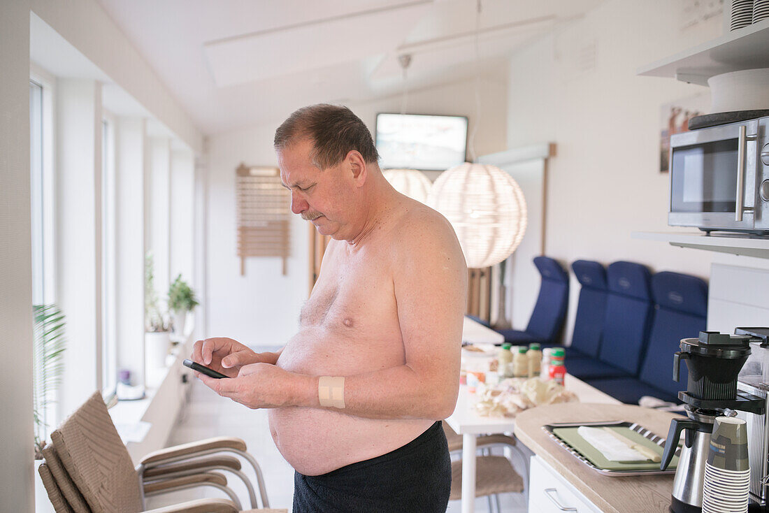 Mann ohne Hemd schreibt eine SMS mit dem Handy