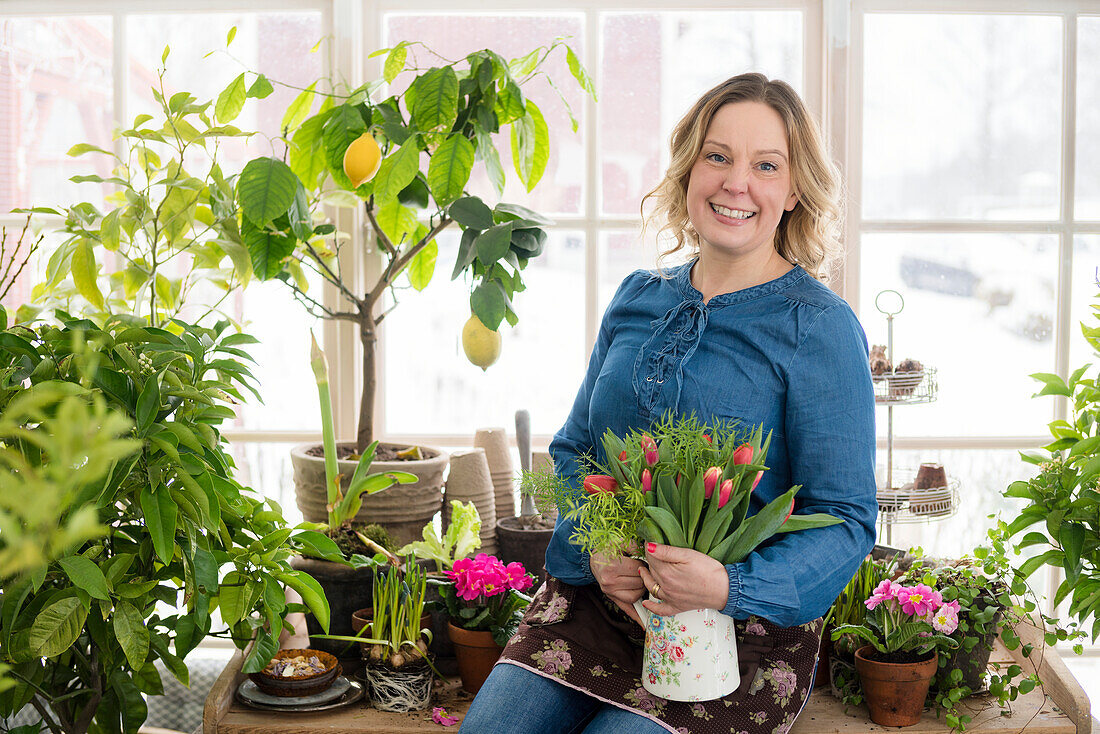 Frau pflanzt Blumen im Wintergarten