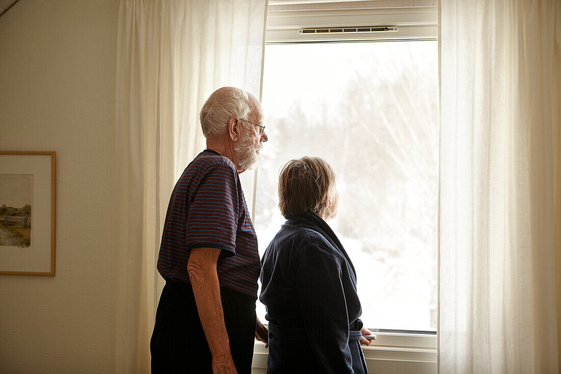 Älteres Paar schaut durch ein Fenster