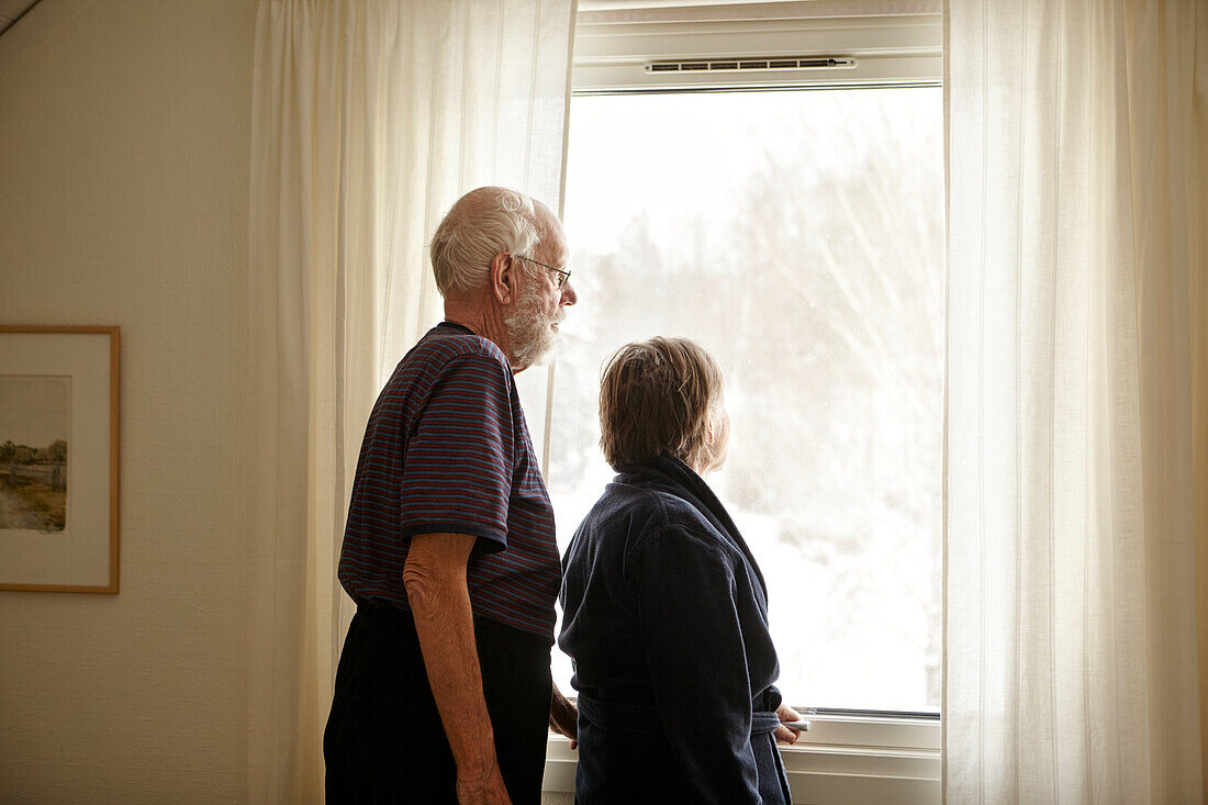 Senior couple looking through window