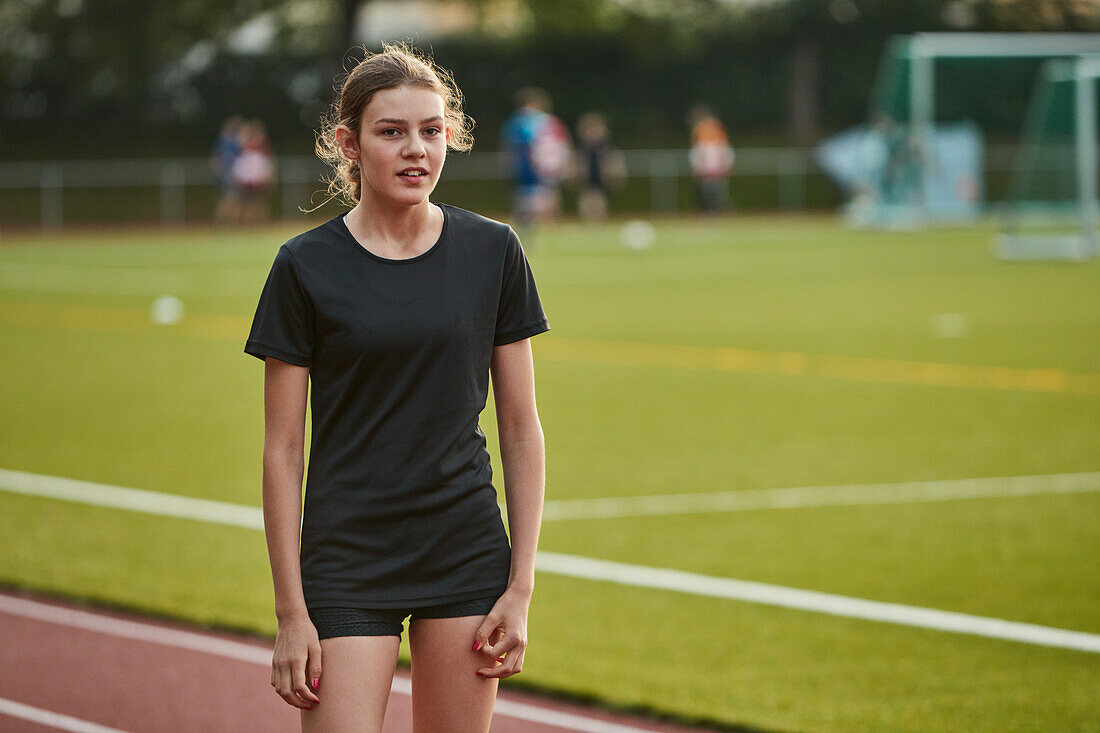 Portrait of teenage girl standing on running track
