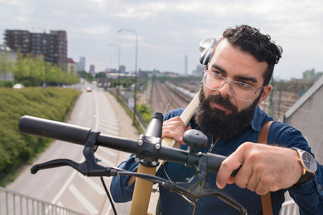 Bearded man carrying bicycle