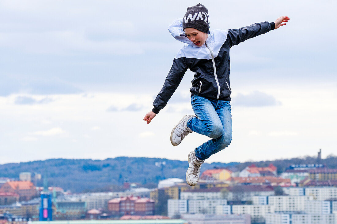 Boy jumping against cityscape