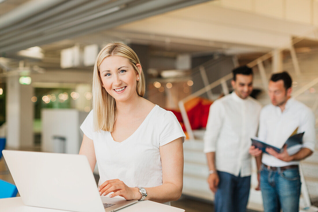 Woman using laptop, looking at camera